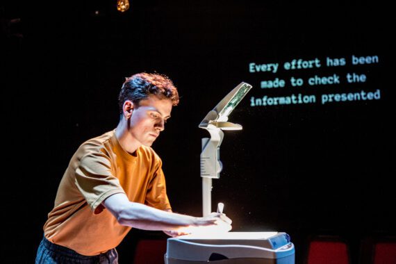 A young man fixing an overhead projector in a dark room.