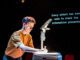 A young man fixing an overhead projector in a dark room.