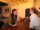 Two women In a pub, lean over the bar chatting.