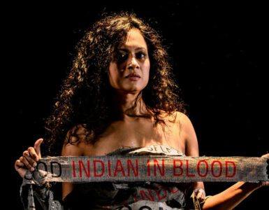 Woman holding material that says "Indian in blood"